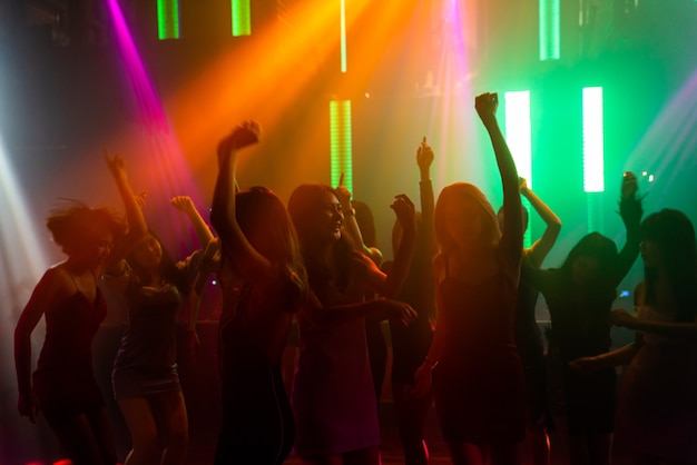 Silhouet van mensen dansen in disco nachtclub op muziek van Dj op het podium