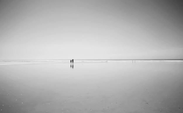 Silhouet van mensen die op het strand lopen
