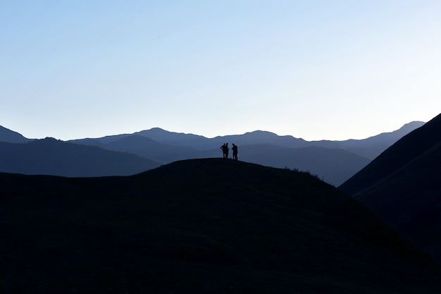 Silhouet van mensen die zich op de heuvel bevinden