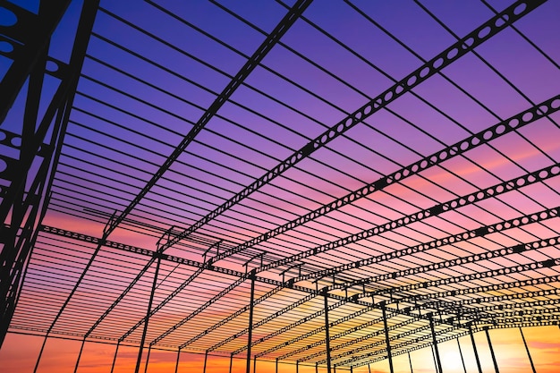 Silhouet van metalen gekanteelde balk van fabrieksbouwconstructie in bouwplaats bij zonsondergang