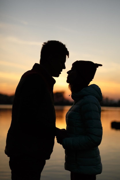 Silhouet van minnaarspaar op zonsondergang bij de meerzon tussen mensenprofielen, schemering, lucht, water aan