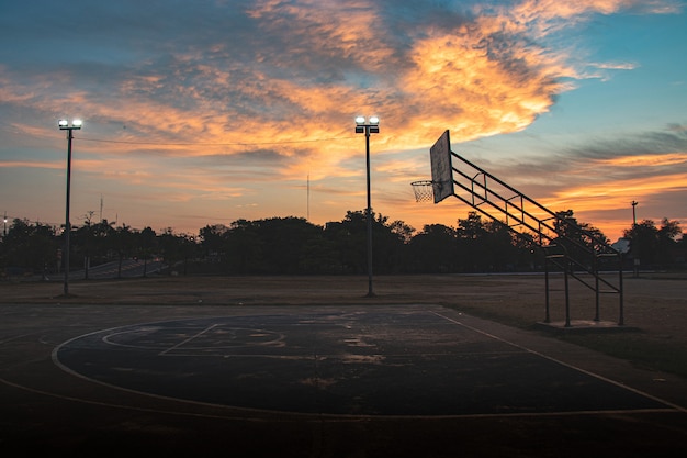 Silhouet van openluchtbasketbalhof met dramatische hemel in de zonsopgangochtend