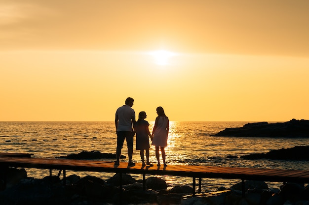 Silhouet van ouders met een kind op zee familie op het strand