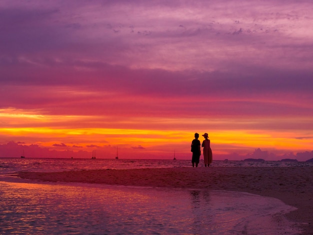 Silhouet van paar in zonsondergangtijd aan zee