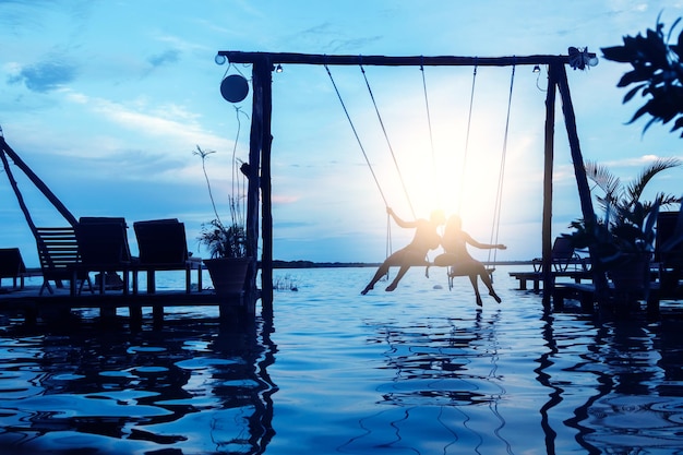 Silhouet van paar op touw schommels op het strand