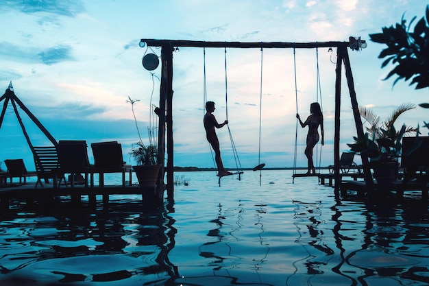 Silhouet van paar op touw schommels op het strand