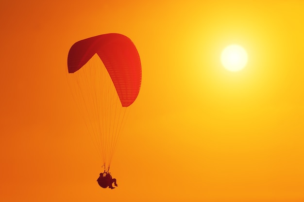 Silhouet van paraglider die bij zonsondergang stijgt