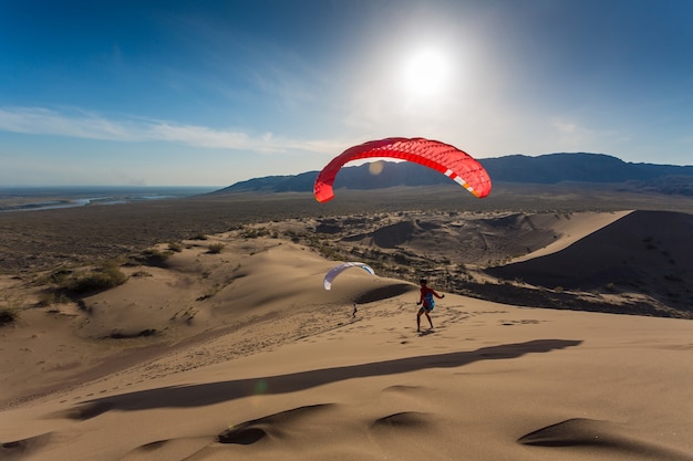 Silhouet van paraglider die in het duin vliegt