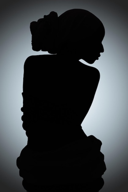 Foto silhouet van schoonheid silhouet shot van een jonge vrouw die zich voordeed tegen een grijze achtergrond