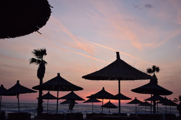 Silhouet van stroparasols bij zonsondergang op het strand