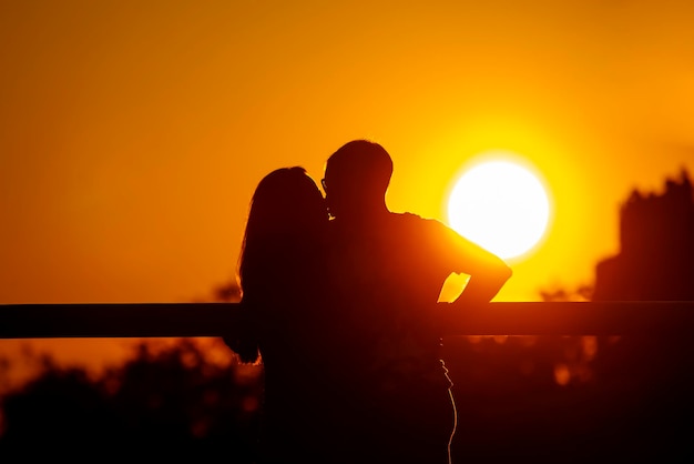 Silhouet van twee verliefde mensen tegen de achtergrond van de ondergaande zon. Romantiek in relaties en natuur