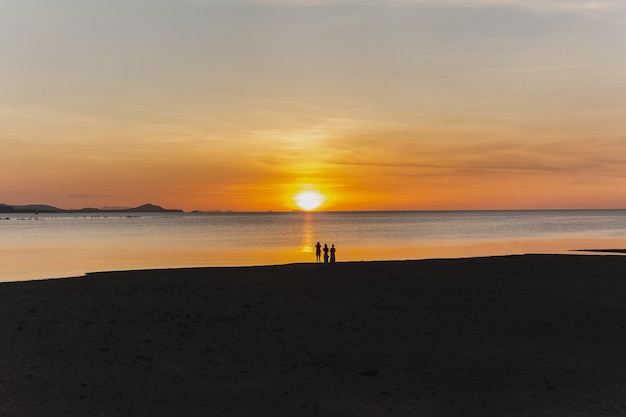 Silhouet van vage mensen die een foto maken van de zonsondergang op het strand