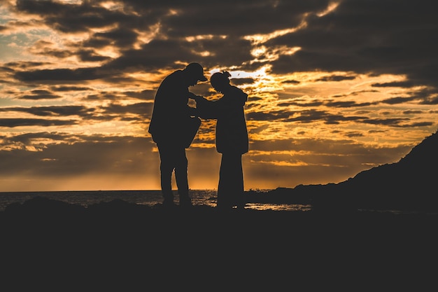 Silhouet van verliefde paar bij zonsopgang Man en vrouw hand in hand aan de kust