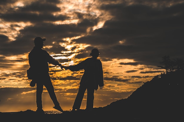 Silhouet van verliefde paar bij zonsopgang Man en vrouw hand in hand aan de kust