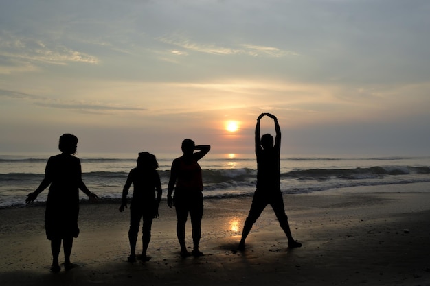 Silhouet van vier mensen die aan de kust spelen bij zonsondergang Gouden uur