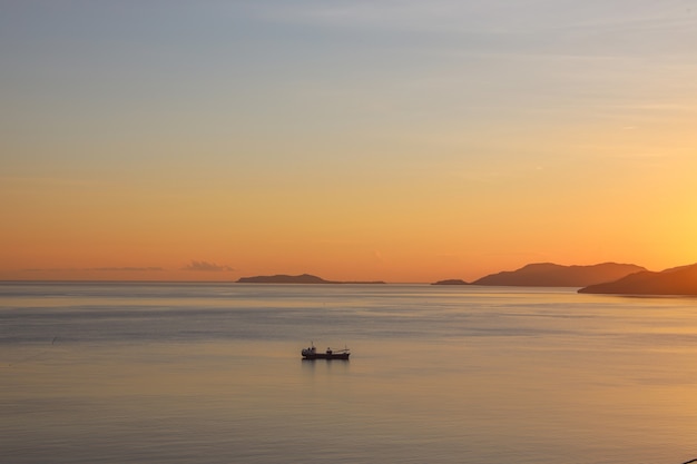 Silhouet van vissersboot zeilen op de zee tijdens zonsondergang