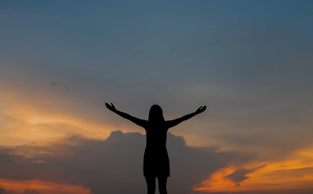 Silhouet van vrouw alleen gelukkig bij zonsondergang