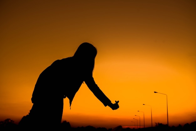 Silhouet van vrouwensymbool van liefde op hemel bij zonsondergang.