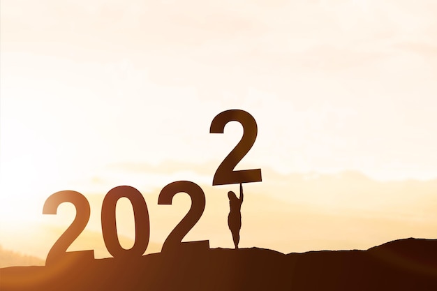 Silhouet van zakenvrouw zet 2022 op de top van de heuvel. gelukkig nieuwjaar 2022