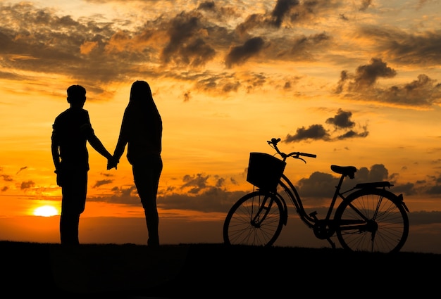 Silhouet van zoet paar in liefde gelukkige tijd en fiets in mooie zonsondergang