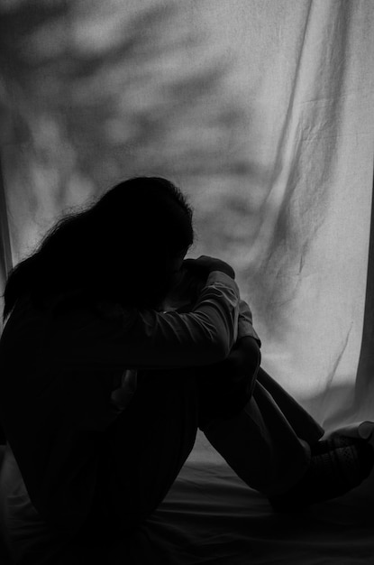 Foto silhouet verdrietige vrouw die in het donker zit