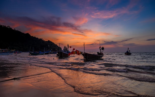 Silhouet vissersboten in de zee met zonsondergang