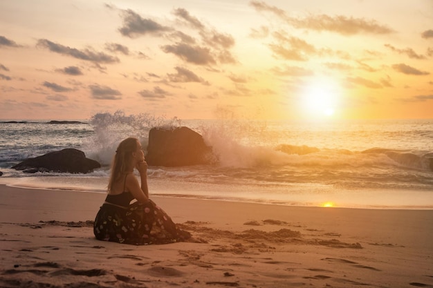 Silhouet vrij romantische vrouw zittend op oceaan strand bij zonsondergang achtergrond en wegkijken Lady op zee strand in zomervakantie