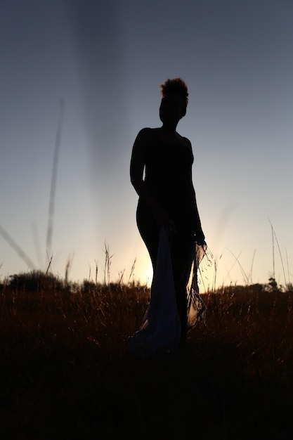 Silhouet vrouw die op het veld staat tegen een heldere lucht