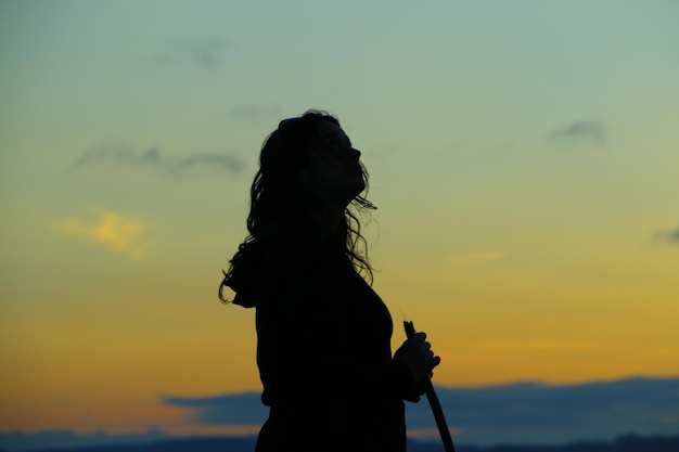 Silhouet vrouw die tegen de hemel staat tijdens zonsondergang