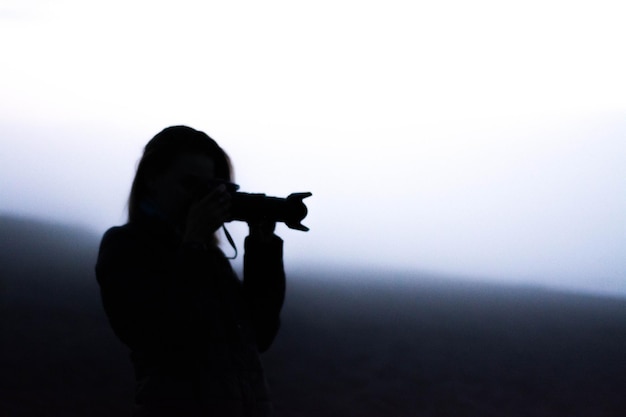 Silhouet vrouw die tegen de lucht fotografeert