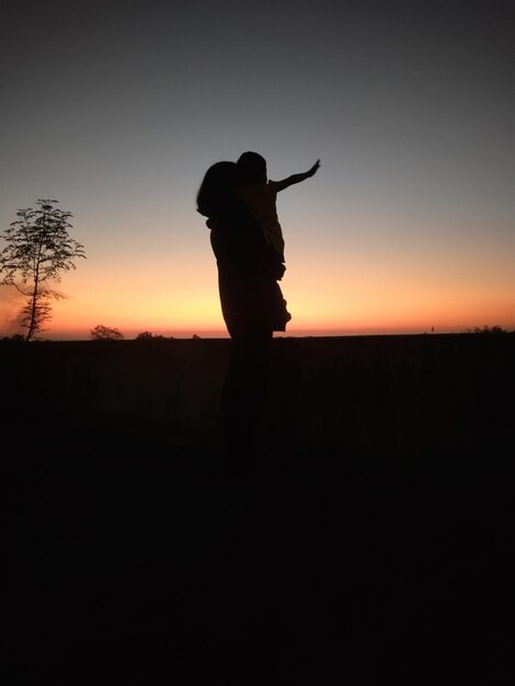 Foto silhouet vrouw die tegen een heldere hemel staat tijdens zonsondergang en probeert degene te zijn die ik was