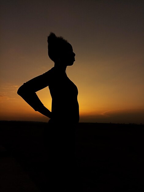 Foto silhouet vrouw die tijdens de zonsondergang op de kust tegen de lucht staat