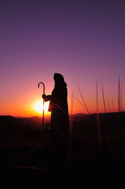 Silhouet vrouw met camera tegen de hemel tijdens zonsondergang