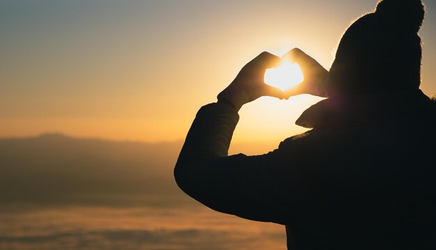 Foto silhouet vrouw met hartvorm tegen de hemel tijdens zonsondergang