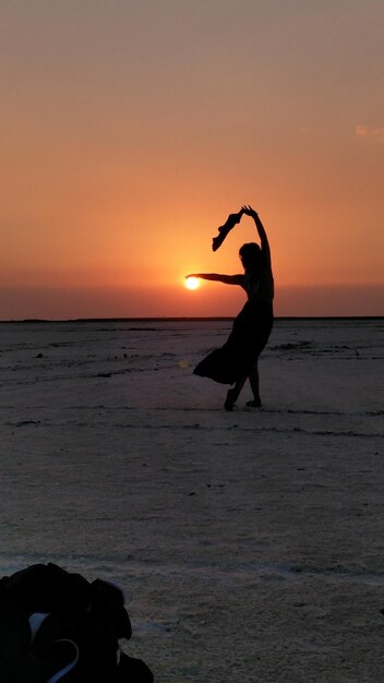 Foto silhouet vrouw op het strand tegen de hemel tijdens zonsondergang