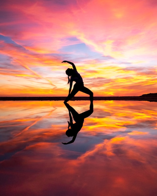Silhouet vrouw op zee tegen de lucht tijdens zonsondergang yoga pose