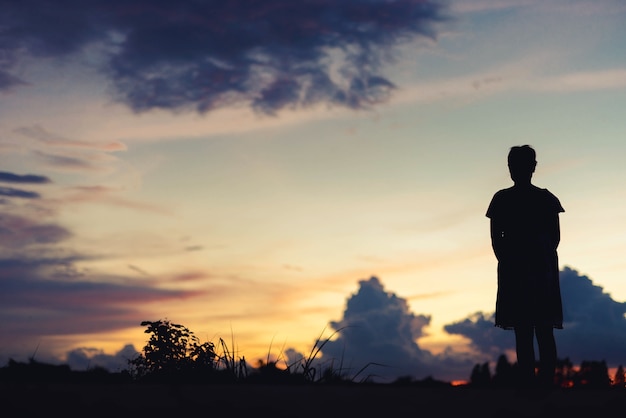 Silhouet vrouw verdrietig staande bij zonsondergang