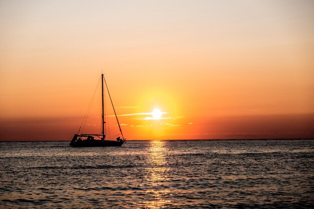 Silhouet zeilboot zeilt op zee tegen de hemel tijdens zonsondergang