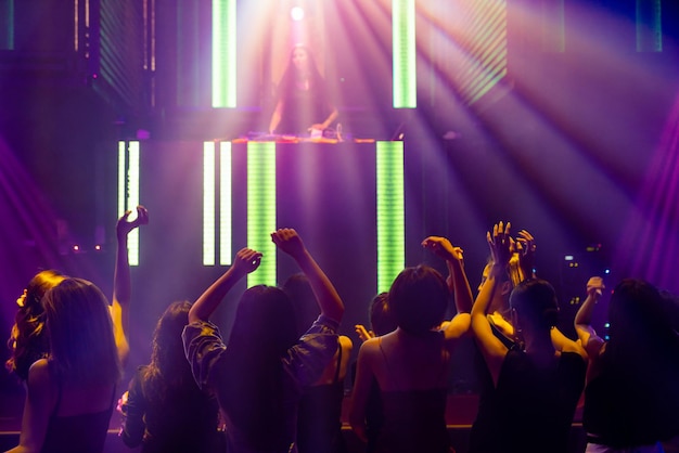 Silhouetbeeld van mensen die dansen in een disco-nachtclub op muziek van DJ op het podium