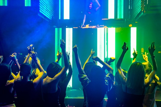 Silhouetbeeld van mensen die dansen in een disco-nachtclub op muziek van DJ op het podium