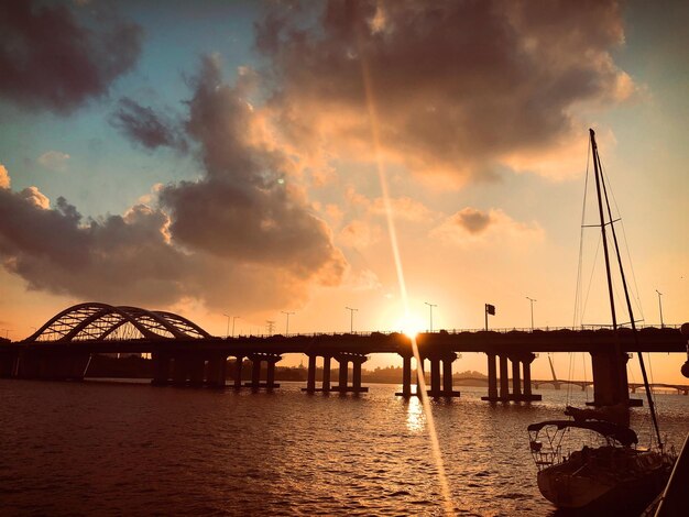 Foto silhouetbrug over de rivier tegen de hemel bij zonsondergang