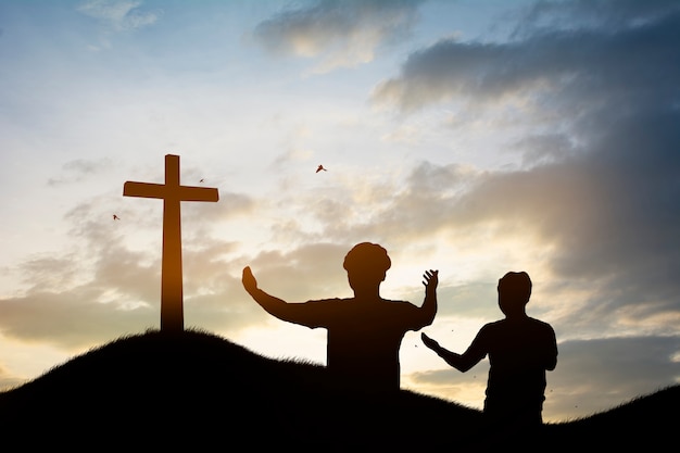 Silhouetfamilie die het kruis van jesus-christus op de herfstzonsopgang zoeken