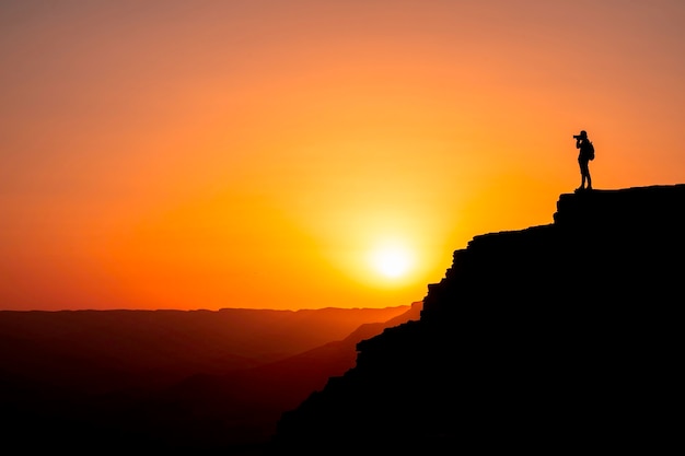 Silhouetfotograaf die een zonsondergang in de bergen schiet. Fotograaf concept