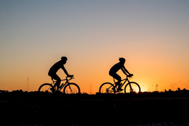 Silhouetgroep mensen die fiets berijden bij zonsondergang.