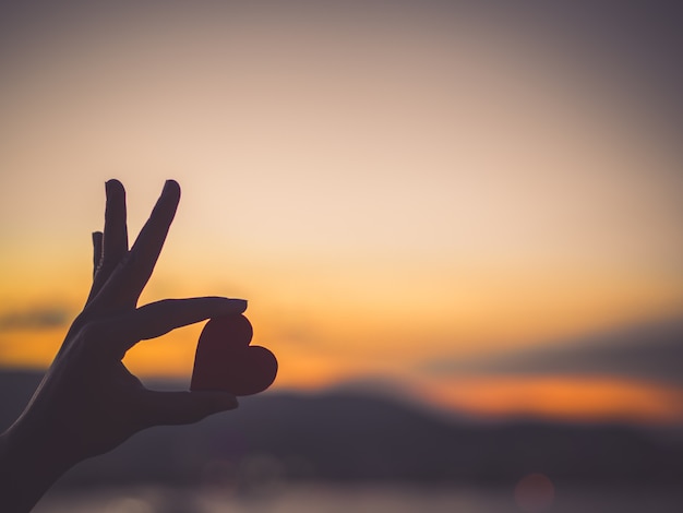 Foto silhouethand die mooi hart houden tijdens zonsondergangachtergrond.