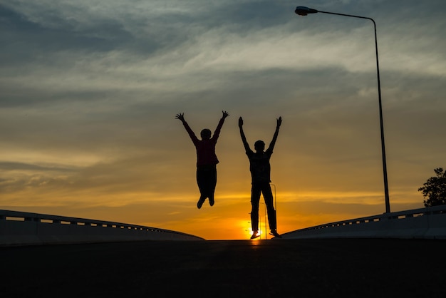 Silhouetparen die bij zonsondergang springen