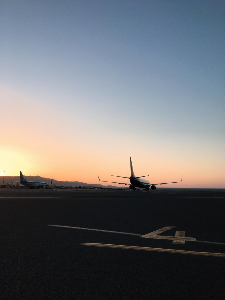 Photo 해가 지는 동안  ⁇ 은 하늘을 배경으로 공항 활주로에 실루 ⁇  비행기