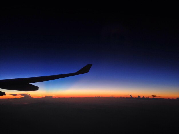写真 夕暮れの晴れた空に照らされた飛行機の翼のシルエット