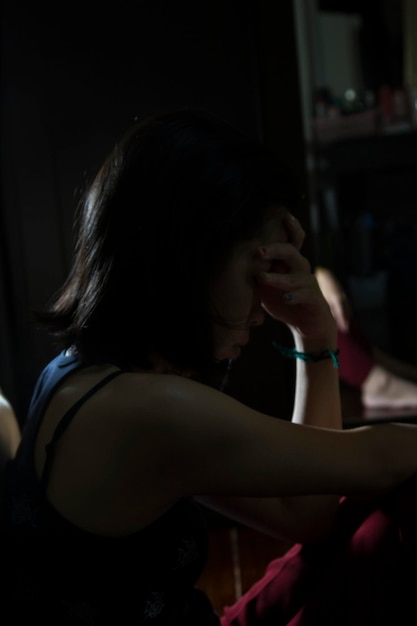 A Silhouette Asian girl close up in the dark room being sad and depressed alone a sad woman sitting