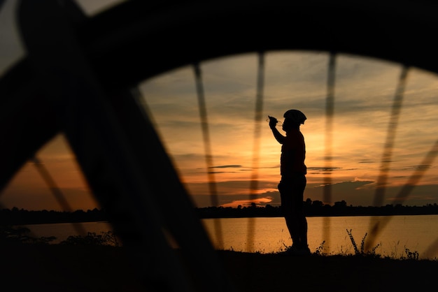 Foto siluetta dell'uomo asiatico giro in bicicletta sul tramonto